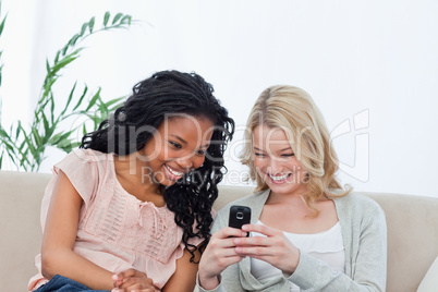 A woman is showing her friend her mobile phone