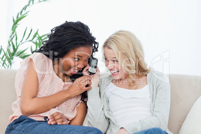 A laughing woman is holding a mobile phone up to her friends ear