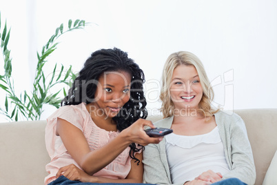 A woman holding a television remote control is sitting longside