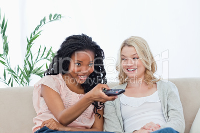 A woman is smiling at her friend who is holding a television rem