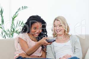 A woman is smiling at her friend who is holding a television rem
