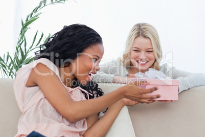 A woman giving a present in a box to her friend