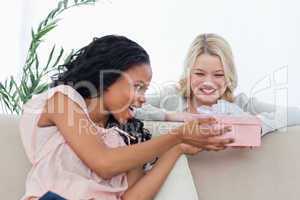 A woman giving a present in a box to her friend