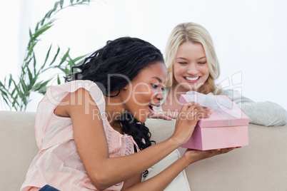 A surprised woman looking in a box given to her from a friend