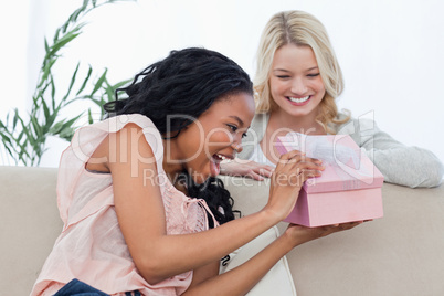 A delighted woman looks at a present given to her by a friend