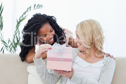 A woman holding a present is smiling at her friend