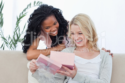 Two smiling women look at a present inside a pink box