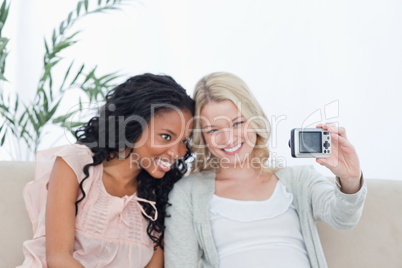 A woman takes a photo of herself and her friend on a digital cam