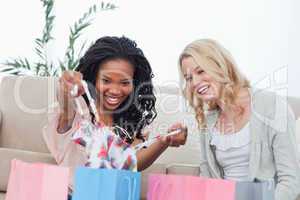 A woman shows her friend clothes she bought