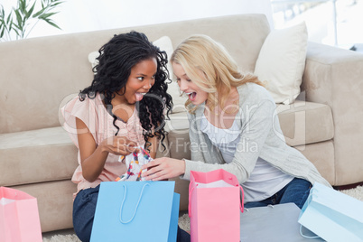 Two women looking at clothes in shopping bags