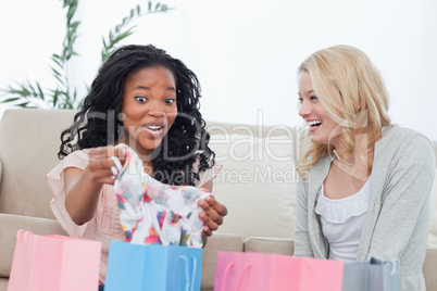 Two laughing women look at clothes they bought