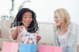 Two laughing women look at clothes they bought
