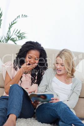 Two surprised women reading a magazine