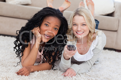 Two women are smiling at the camera and lying on the ground