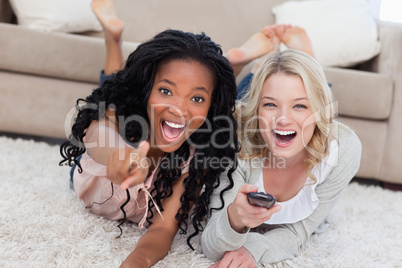 Two laughing women are lying on the ground and looking at the ca