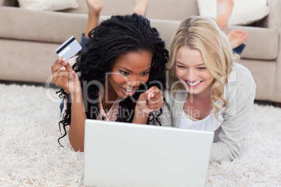 A woman holding a bank card is lying on the floor with her frien