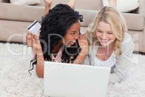A woman holding a bank card is is smiling at her friend who has