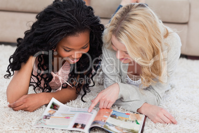 Two women lying on the floor with a magazine in front of them