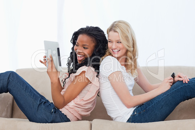 A woman leaning up against her friends back is holding a tablet