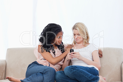 A sad woman sitting on a couch with her friend is looking at her