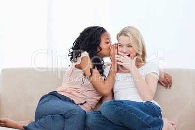 A woman is whispering into her shocked friends ear