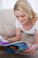 A woman is lying down reading a magazine
