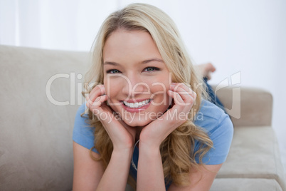 A smiling woman is resting her head on her hands