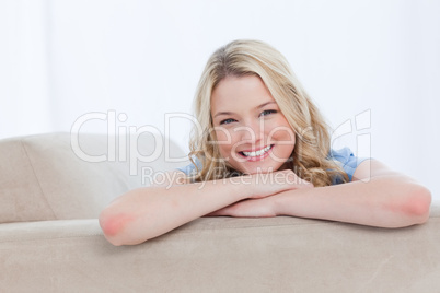 A smiling woman is resting her chin on her hands