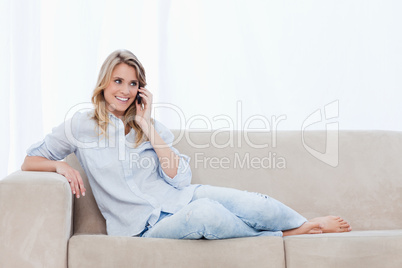 A woman on a couch is talking on her mobile phone