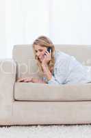 A woman resting on her elbows is talking on her mobile phone