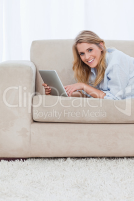 A woman smiling at the camera is holding a tablet