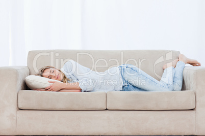 A woman is lying on a couch sleeping