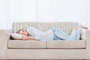 A woman is lying on a couch sleeping