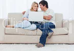 A young couple sitting on a couch with a laptop