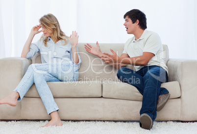 A man is having an argument with his girlfriend while sitting on