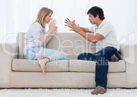 A couple sitting on a couch are having an argument