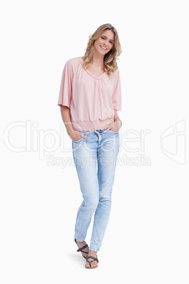A smiling woman is standing with her hands in her pockets