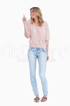 A smiling woman is pointing upwards