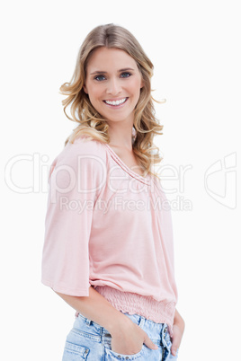 Side view shot of a woman with her hands in her pocket smiling a
