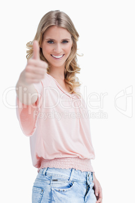 A blonde woman with her thumb up smiling at the camera