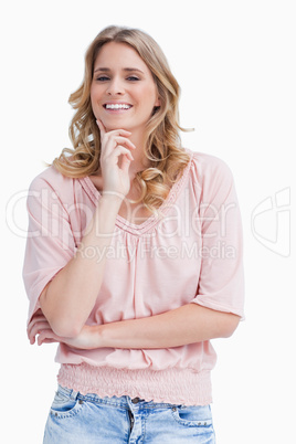 A woman smiling at the camera is resting her chin on her hand