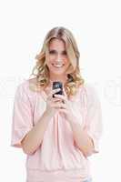A woman holding a mobile phone is looking at the camera