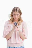 A woman with a serious expression is looking at her mobile phone