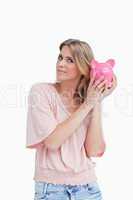 Woman holding a piggy bank up to her head