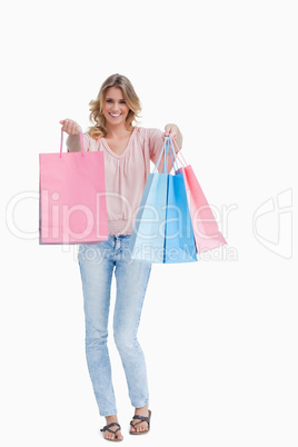 A woman is standing holding up shopping bags