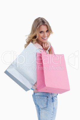 A woman looking back at the camera is carrying shopping bags ove