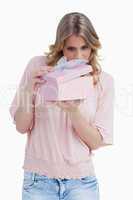 Curious young woman holding a gift while opening it