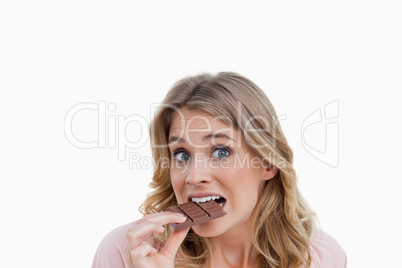 Young blonde woman looking at the camera while eating chocolate