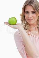 Young woman holding a green apple while looking at the camera