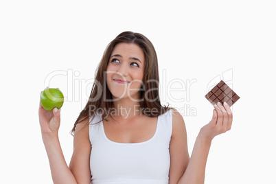Relaxed young woman holding an apple and chocolate